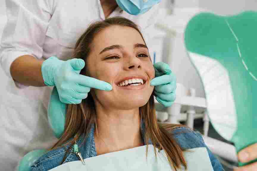 a-woman-smiling-while-looking-at-mirror-in-trust-care-dental-clinic.